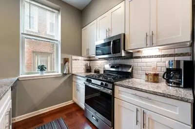 a kitchen with white cabinets and a stove top oven at Large 3 bdrm apt, 2ba, unique art in Philadelphia