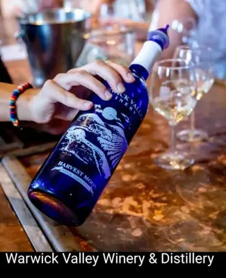 a person is holding a blue wine bottle on a table at Great Gorge-ous condo in Vernon Township