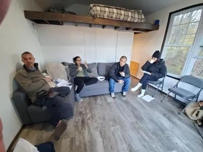 a group of people sitting on a couch in a room at Catskills tiny house cabin in Livingston Manor