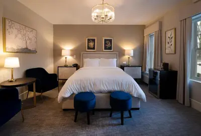 a bedroom with a bed and two chairs and a chandelier at Orange Inn Boutique Hotel in Goshen