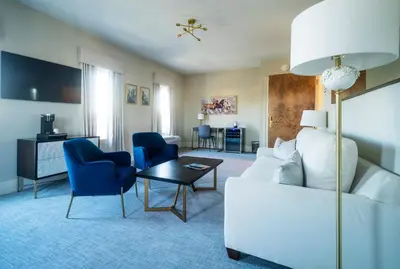 a living room with a white couch and blue chairs at Orange Inn Boutique Hotel in Goshen