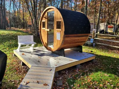 a wooden cabin with a chair on a wooden platform at Spacious Home by Kalahari Waterpark, Camelback, Jim Thorpe, FREE EV and PRIVATE SAUNA in Albrightsville
