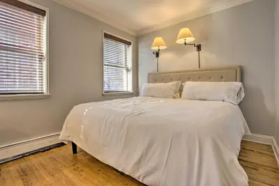 a bedroom with a large white bed with two windows at Hoboken Condo Walk to Public Transit! in Hoboken