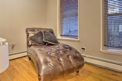 a brown leather chair in a room with two windows at Hoboken Condo Walk to Public Transit! in Hoboken