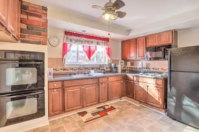 a kitchen with wooden cabinets and stainless steel appliances at Cozy Townhome about 12 Mi to Downtown Philly!