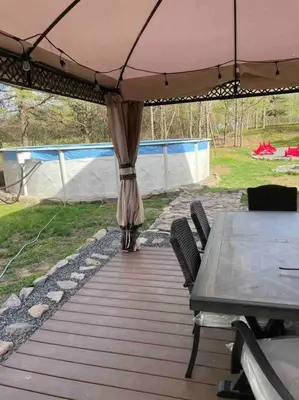 a table and chairs under an umbrella on a deck at Quiet Private House w Hot Tub/Fire pit/Games in Blakeslee