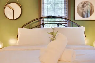 a bedroom with a bed with white pillows and a mirror at Lake View Enchanted Treehouse- Lake Harmony in Lake Harmony
