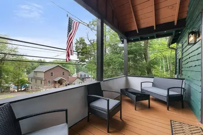 a balcony with chairs and an american flag at Lake View Enchanted Treehouse- Lake Harmony in Lake Harmony