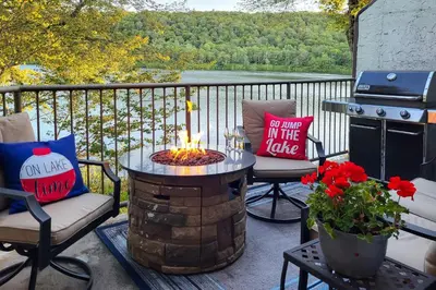 a fire pit on a patio with a view of a lake at Game Room and BBQ Waterfront Lake Harmony Condo! in Lake Harmony