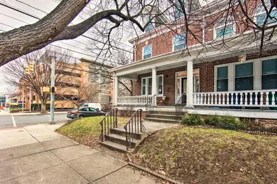 a brick house with a white porch on a street at Lancaster Unit with Expansive Covered Porch! in Lancaster