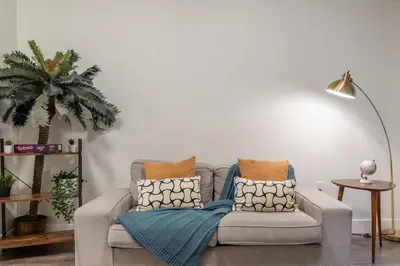 a living room with a couch and a palm tree at Blue Breakaway with Free Parking and Sleeps 9, Book 7 days, Get 20 Percent OFF in East Orange