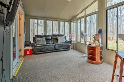 a living room with a leather couch and windows at Walk to Locust Lake Poconos Vacation Home! in Pocono Lake