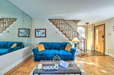 a living room with a blue couch and stairs at Yeadon Townhome with Porch, 7 Mi to Center City in Drexel Hill