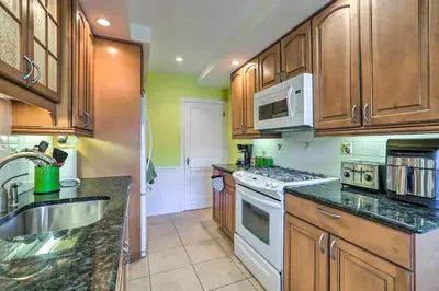 a kitchen with wooden cabinets and a white stove top oven at Yeadon Townhome with Porch, 7 Mi to Center City in Drexel Hill