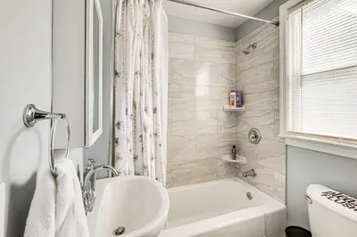 a bathroom with a white tub and a sink at Updated Linden Home Visit NYC and Newark! in Linden