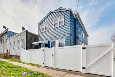 a blue house behind a white fence at Updated Linden Home Visit NYC and Newark! in Linden