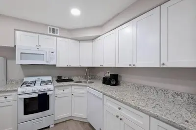 a kitchen with white cabinets and a stove and microwave at Newly Built 2 Bdrm-By Philly Center City in Philadelphia