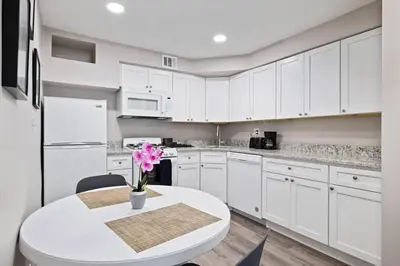 a kitchen with white cabinets and a white table with pink flowers at Newly Built 2 Bdrm-By Philly Center City in Philadelphia