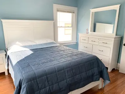 a bedroom with a bed and a dresser and a mirror at Newly renovated 4 bedroom apartment near downtown. in Montclair