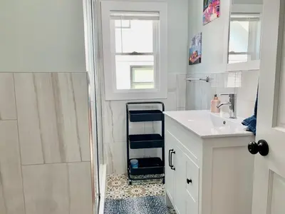 a white bathroom with a sink and a shower at Newly renovated 4 bedroom apartment near downtown. in Montclair
