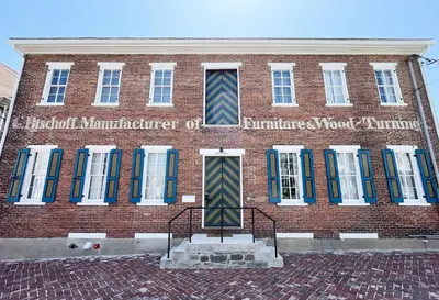 a red brick building with blue and green windows at Bischoff Inn - Former 1870 Furniture Factory Now 5 Room Boutique Hotel in Tamaqua