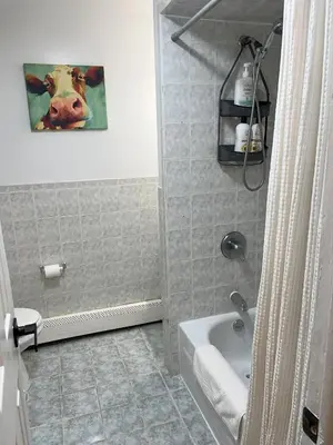 a bathroom with a tub and a painting of a cow at Two Bedroom Private Apt near NYC in West New York