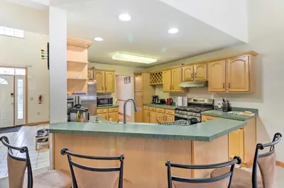 a large kitchen with wooden cabinets and a counter top at Game Room Poconos Family Home 13 Mi to Skiing! in Tobyhanna