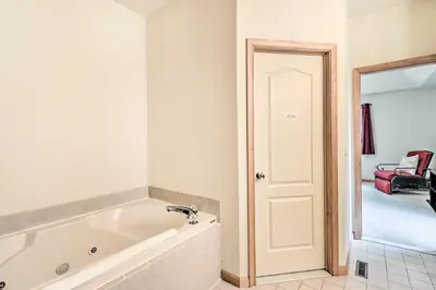 a white bath tub in a bathroom next to a door at Game Room Poconos Family Home 13 Mi to Skiing! in Tobyhanna