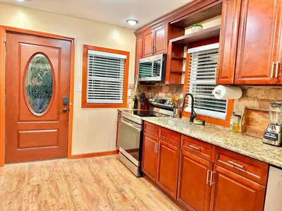 a kitchen with wooden cabinets and a red door at Chic Chalet River Views & Access in Montague