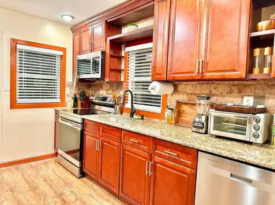 a kitchen with wooden cabinets and stainless steel appliances at Chic Chalet River Views & Access in Montague