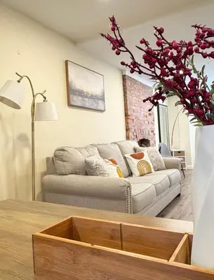 a living room with a couch and a vase with flowers at Classical Isbills Row House close to NYC in Bayonne