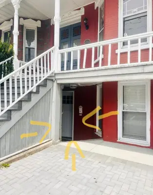 a house with yellow arrows painted on the side of it at Classical Isbills Row House close to NYC in Bayonne