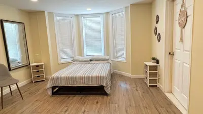 a bedroom with a bed in a room with windows at Classical Isbills Row House close to NYC in Bayonne