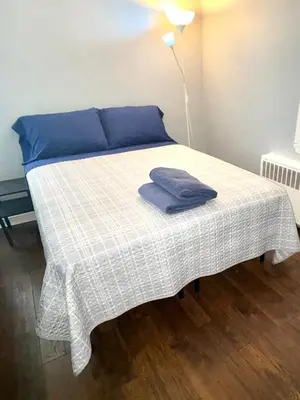 a bed with a blue pillow and a blanket on it at Cozy Apartments close to New York City in North Bergen