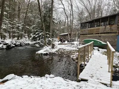 a river with snow on the ground next to a building at Peaceful Gateway to Island Creek Cottage in East Stroudsburg