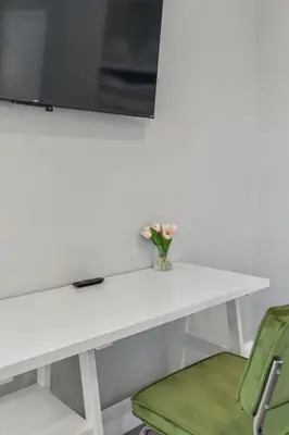 a white table with a vase of flowers and a green chair at Stay at Luna on N 11th St in Philadelphia