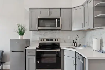 a kitchen with white cabinets and a black stove top oven at Stay at Luna on N 11th St in Philadelphia