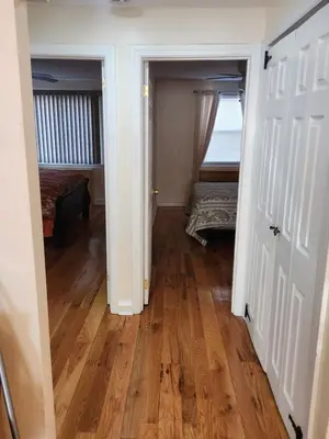 a hallway with a room with two beds and wooden floors at Cozy 2-bedroom Apartment in Philadelphia