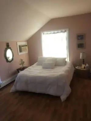 a bedroom with a large white bed with a window at Peddlers Carriage house in New Hope