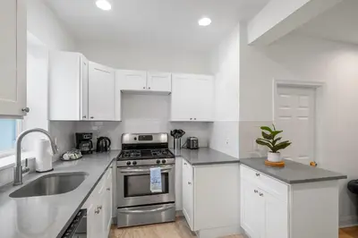 a kitchen with white cabinets and a stainless steel stove at Luxury 3BR Townhome - Northern Liberty in Philadelphia