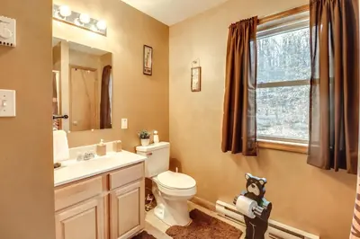 a bathroom with a toilet and a sink and a window at Less Than 1 Mi to Ski Hill! Poconos Retreat with Game Room in Pocono Lake