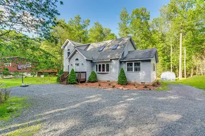 a white house with a gambrel roof on a driveway at Less Than 1 Mi to Ski Hill! Poconos Retreat with Game Room in Pocono Lake