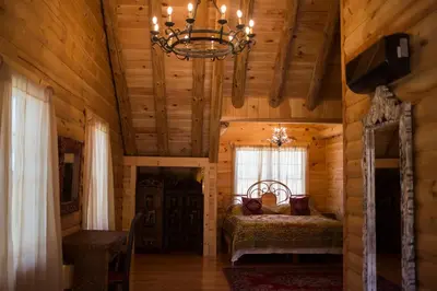 a bedroom in a log cabin with a chandelier at Log Country Inn Bed and Breakfast of Ithaca in Spencer