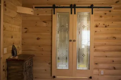 two glass doors in a room with wooden walls at Log Country Inn Bed and Breakfast of Ithaca in Spencer