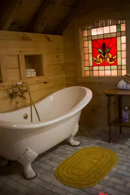 a bath tub in a room with a stained glass window at Log Country Inn Bed and Breakfast of Ithaca in Spencer
