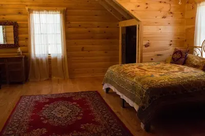 a bedroom with a bed in a log cabin at Log Country Inn Bed and Breakfast of Ithaca in Spencer