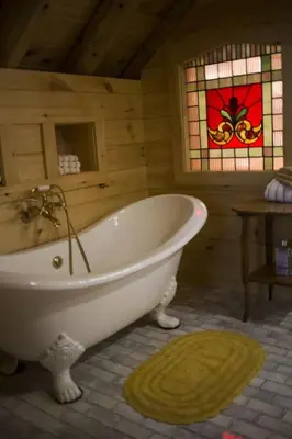 a bath tub in a room with a stained glass window at Log Country Inn Bed and Breakfast of Ithaca in Spencer