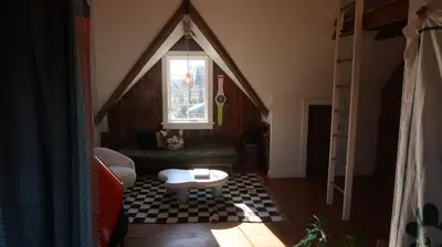 a room with a couch and a window in a attic at Creative Private Attic 1br Suite in Honey Brook
