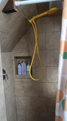 a shower with a yellow hose in a bathroom at Creative Private Attic 1br Suite in Honey Brook