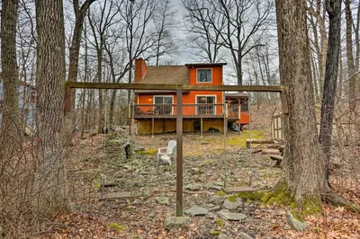 an orange house in the middle of the woods at 4 Mi to Tubing Cozy Bushkill Cabin with Deck! in Bushkill